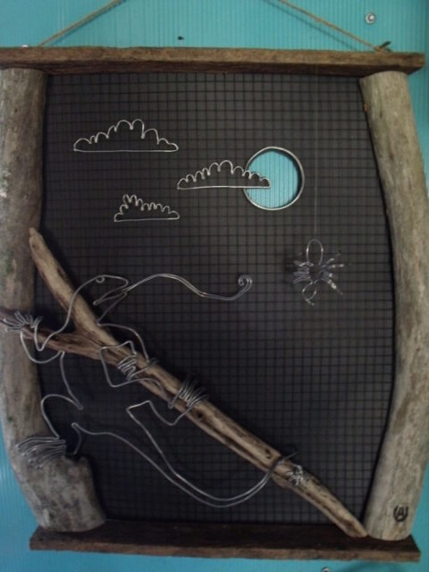 Recycled wood and wire sculpture of a Lizard after a spider with a sky setting