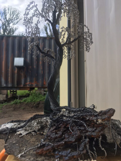 Live Wire Sculptures new Blackened Wire Trees on the base of black pumice stone & molten metal left from the South Coast Fires, sitting outside on the property