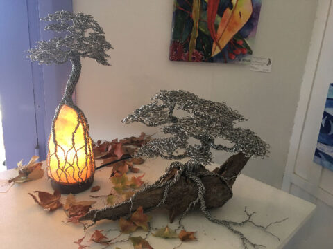 Livewire Sculpture's Himalayan Salt Lamp Tall Tree lit up next to another Live Wire recycled wire & driftwood tree in the Lazy Lizard Gallery in Cobargo